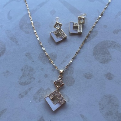 Conjunto de colar e brincos dourados com pendentes geométricos e pedras brilhantes