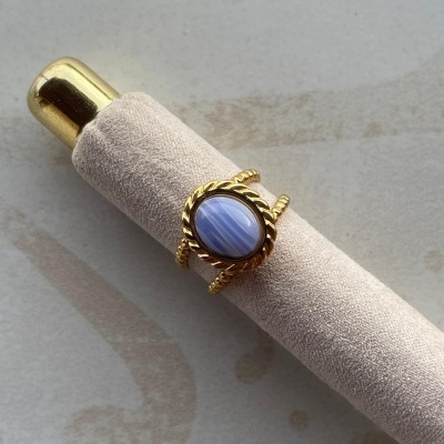 Anel dourado com pedra azul em suporte de veludo bege