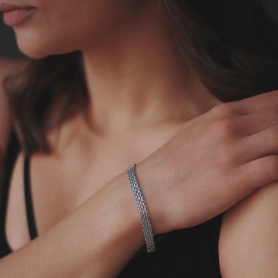 Pulseira metálica prateada fina no pulso de mulher com top preto