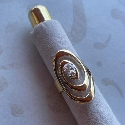 Anel dourado com pedra transparente em suporte de veludo cinza claro