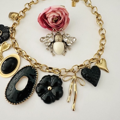 Colar dourado com pendentes pretos variados e pendente de abelha decorada.