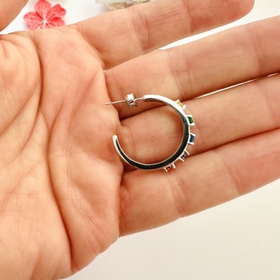 Brinco argola prateado com pedras coloridas na mão