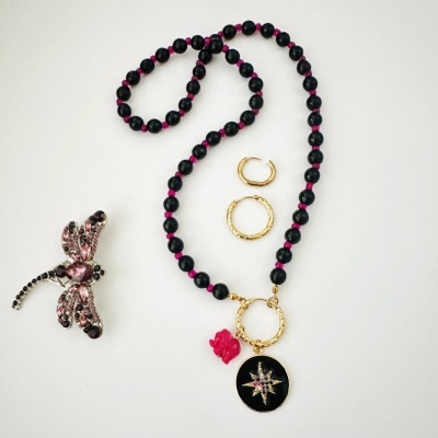 Colar de contas pretas com pendentes dourado e rosa, dois brincos dourados e broche de libélula com cristais rosa e pretos.
