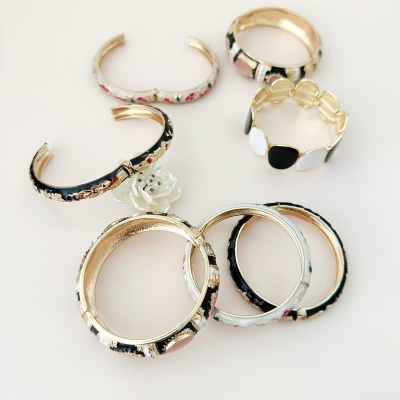 Pulseiras e braceletes metálicos com esmalte colorido e pedras em fundo branco