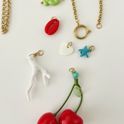 Colares e pendentes dourados com vários pendentes coloridos sobre fundo branco