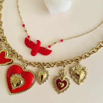 Colares dourados com pendentes de corações vermelhos e pássaro vermelho sobre fundo branco