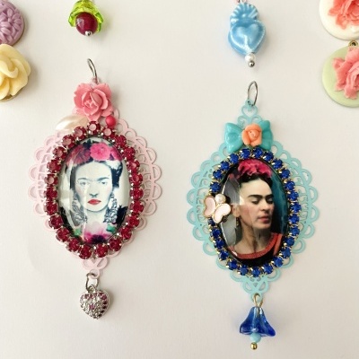 Duas molduras ovais com fotos da pintora Frida Kahlo e enfeites coloridos sobre fundo branco.