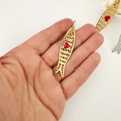 Bijuteria dourada em forma de peixe com coração vermelho na mão
