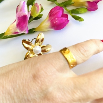 Anel dourado com textura e bague flor dourada com pérola, flores amarelas e roxas