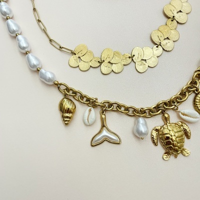 Três colares sobre fundo bege com pérolas, folhas douradas e pingentes marinhos.