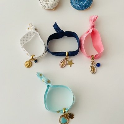 Bijuterias diversas incluindo brincos em formato espiral e pulseiras coloridas com pendentes dourados