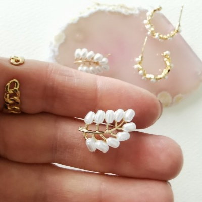 Brincos em metal dourado com pérolas brancas, argolas douradas e anel sobre pedra roxa translúcida