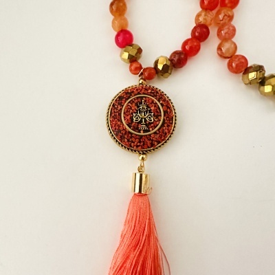 Colar com contas vermelhas e douradas com pendente circular e pompom coral