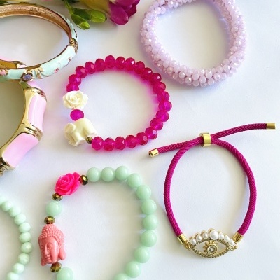 Cinco pulseiras femininas coloridas com diferentes materiais e detalhes sobre fundo branco.