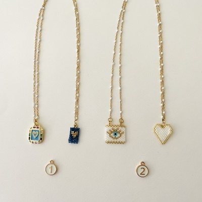 Colares com pendentes de contas coloridas e etiquetas numeradas 1 e 2 pendurados em fundo claro