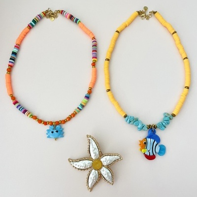 Duas pulseiras coloridas com pendentes e um broche em forma de estrela do mar
