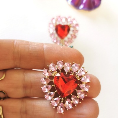 Brincos coração com pedras vermelhas e rosas em fundo branco