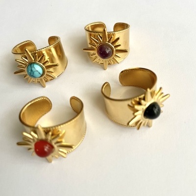 Quatro anéis dourados com pedras coloridas e detalhe de sol sobre fundo branco