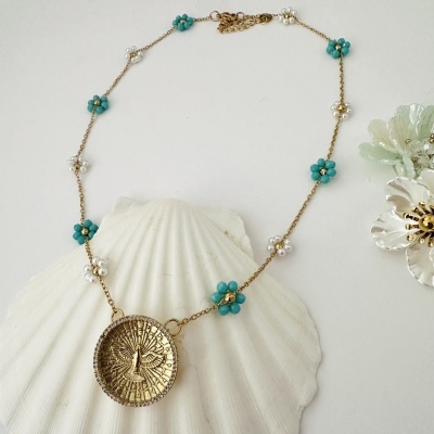 Colar dourado com flores de contas azuis e brancas e pendente redondo com desenho de pássaro