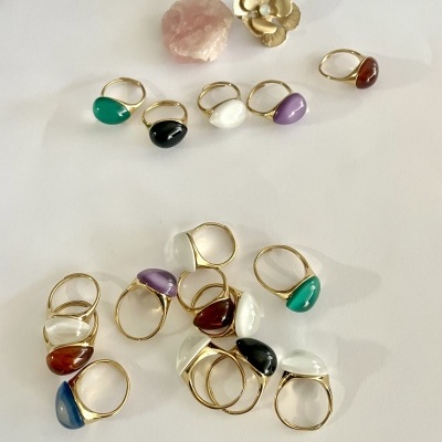 Anéis coloridos com bandas douradas e decoração de flor dourada e pedra rosa