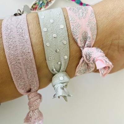 Três pulseiras elásticas de tecido com nós, usadas no pulso
