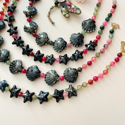 Colares coloridos com contas em formas de conchas e estrelas sobre superfície clara