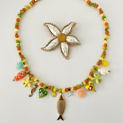 Colar colorido com pingentes variados e broche em forma de flor branca e dourada