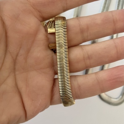 Pulseira dourada com textura ondulada segurada por uma mão