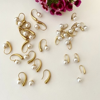 Brincos dourados com pérolas e flores roxas sobre fundo branco