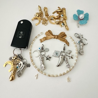 Peças de bijuteria com charms variados em metal dourado e prateado e chave de carro preta