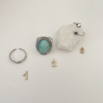 Conjunto de joias com anel de pedra azul, argola, brincos de coração e pendentes 1, 2, 8 sobre fundo branco