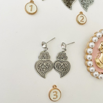 Brincos de metal em formato de coração com etiquetas numeradas e broche com moldura de pérolas