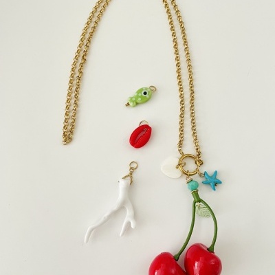 Colar dourado com pendentes coloridos, incluindo cerejas, coral, concha, estrela do mar, folha e peixe.