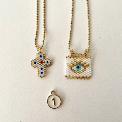 Colares com pendentes de contas douradas e brancas e pendente redondo com número 1