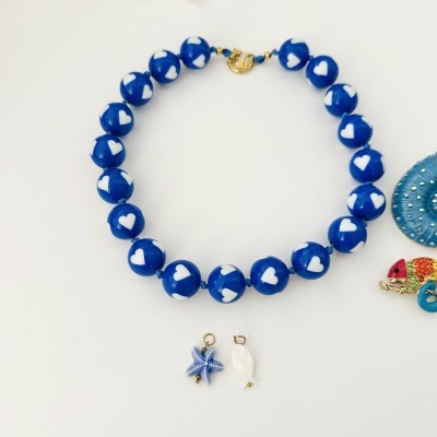 Colar azul com corações brancos e pendentes marinhos em fundo branco