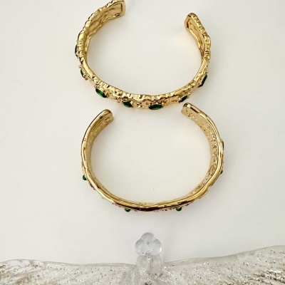 Braceletes dourados com pedras verdes e escultura de vidro translúcido com glitter