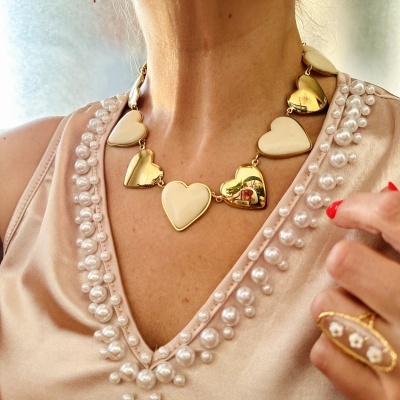 Colar de corações dourados e bege com anel dourado e pérolas em camisola rosa bordada