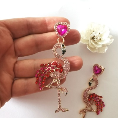 Brincos de flamingo dourados com pedras cor de rosa e vermelhas e coração rosa