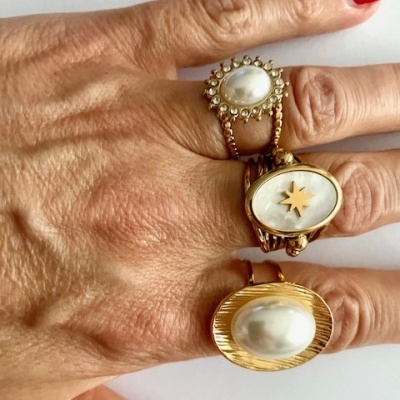 Três anéis dourados com pedras brancas em mão feminina