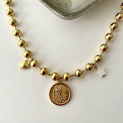 Colar dourado com pendentes e prato prateado ao fundo