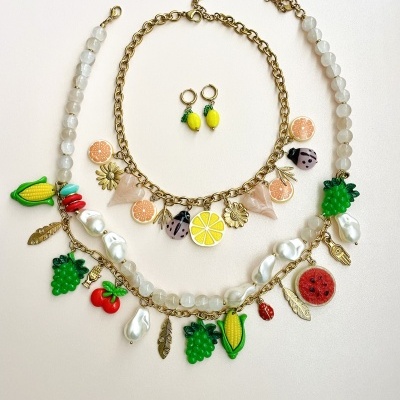 Conjunto colorido de bijuteria com frutas e pérolas sobre fundo branco