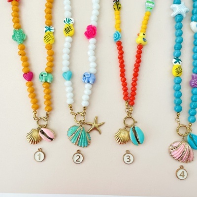 Cinco colares coloridos com pingentes de conchas e números pendurados.