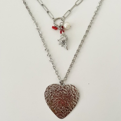 Três colares prateados com pendentes variados sobre fundo branco