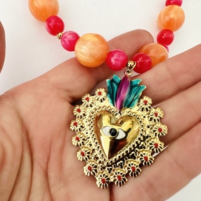Colar com contas laranja e vermelho com pendente dourado em forma de coração com olho e detalhes florais