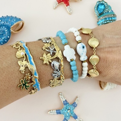 Pulseiras marítimas douradas, azuis e brancas com conchas e estrelas do mar no braço, fundo claro com estrelas do mar decorativas