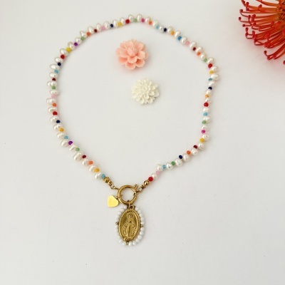 Colar de pérolas com contas coloridas e pendente dourado sobre fundo branco com flores decorativas.