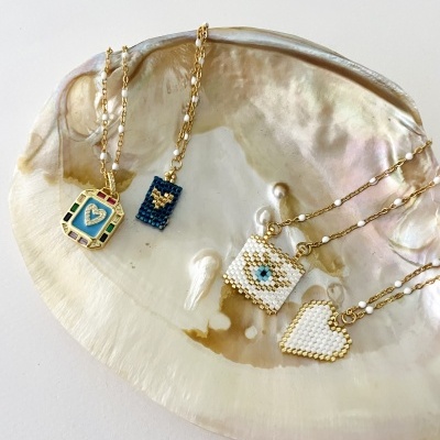 Colares com pendentes em contas variadas sobre concha perolada