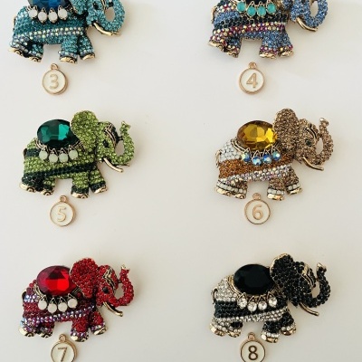 Broches de elefantes coloridos com pedras, numerados, sobre fundo branco
