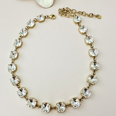 Colar choker com pedras transparentes em metal dourado com fundo claro e decoração de pérolas e flor