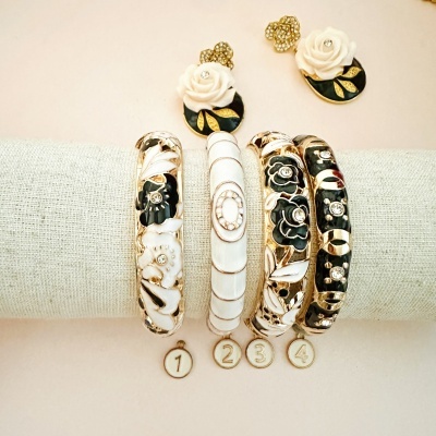 Conjunto de pulseiras e brincos com flores em esmalte preto e branco e detalhes dourados